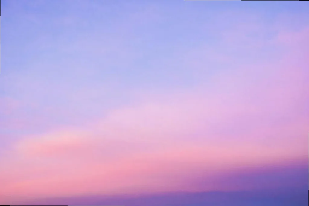 A breathtaking sunset sky painted in soft pink and ethereal purple hues, creating a dreamy golden hour aesthetic.