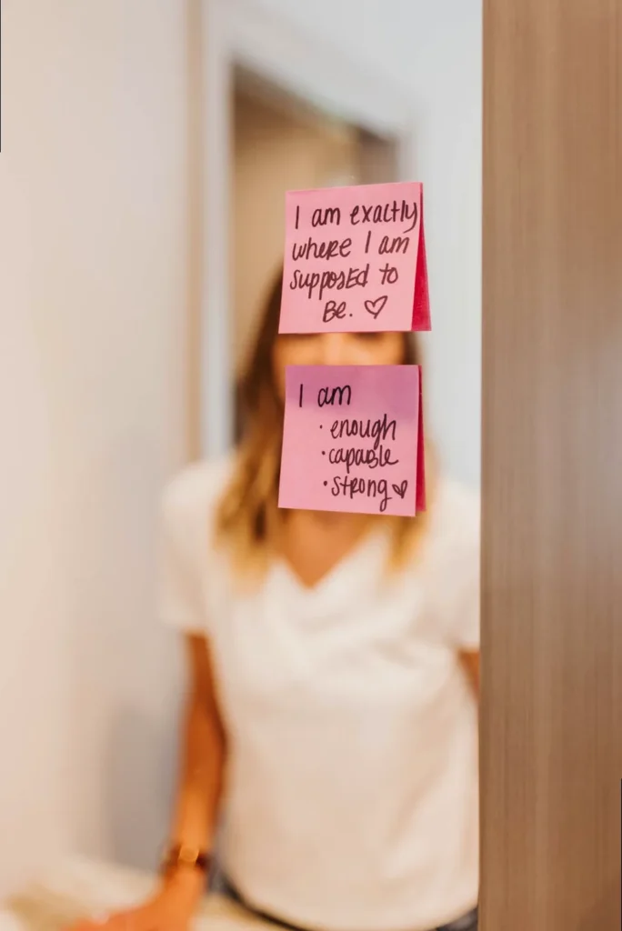 Close-up of a bathroom mirror adorned with handwritten self-affirmation notes and positive quotes, promoting daily self-love and encouragement.