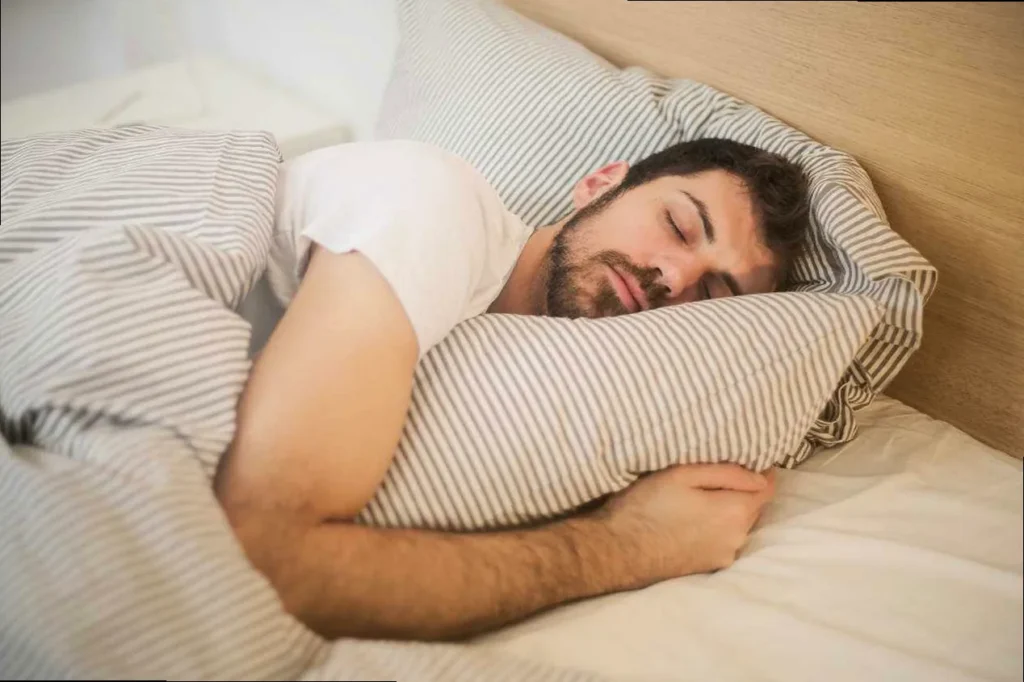 Man sleeping in bed dreaming about good night messages from his long-distance partner, depicting longing and peace.