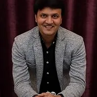 A thoughtful engineer, possibly Amit Kalantri, with gears and blueprints, symbolizing the power of ideas in mechanical engineering.