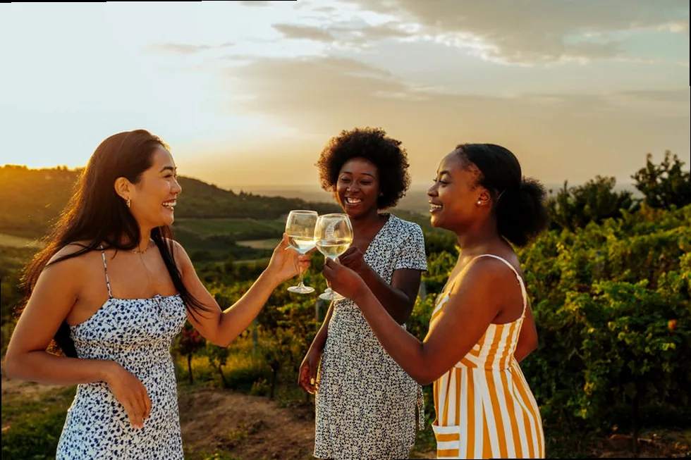 Three female friends toasting wine in a vineyard, symbolizing sweet and cherished friendship.