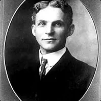 Henry Ford, an automotive pioneer, deep in thought amidst early machinery, symbolizing industrial innovation and breaking boundaries.