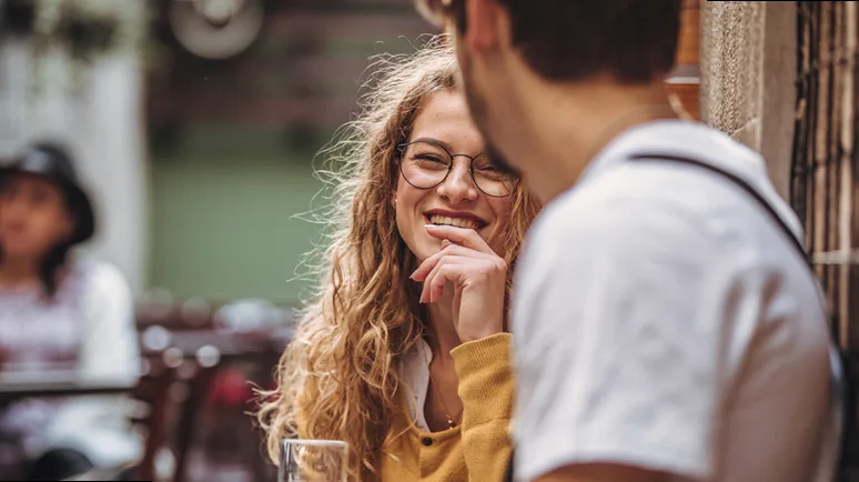 A couple laughing together over coffee, finding humor in their dating experiences.