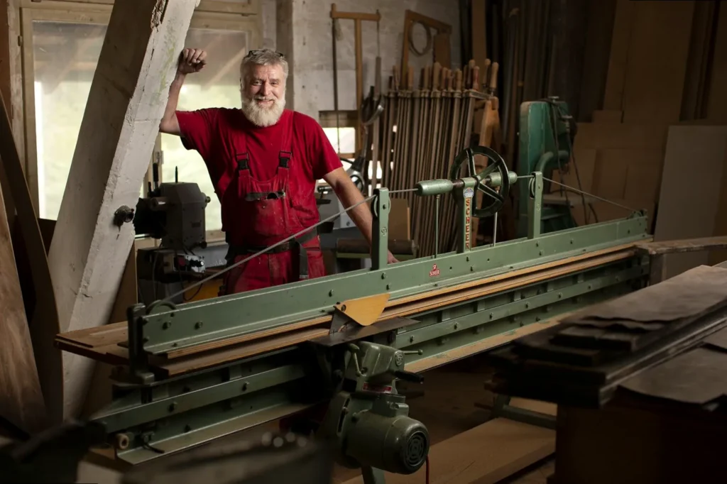 Environmental portrait of a carpenter working in his studio, surrounded by tools and wooden creations.