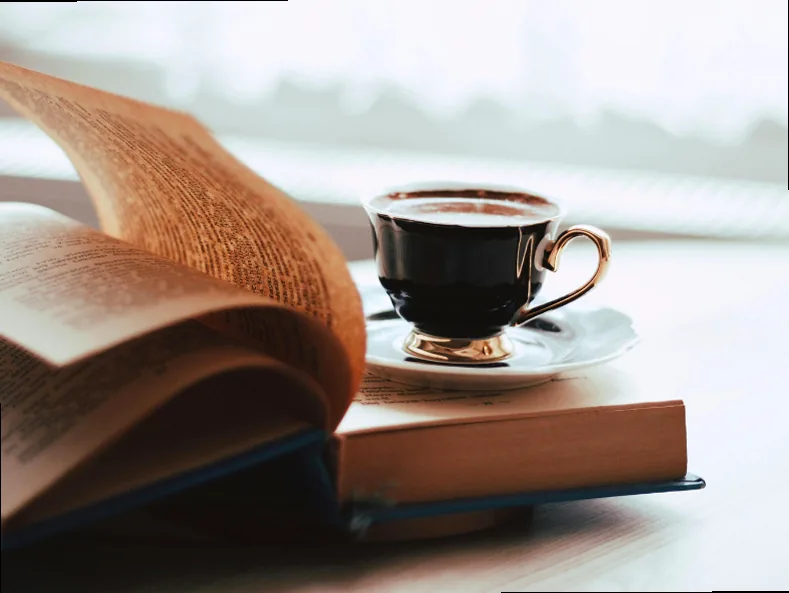 An open book with a cup of coffee resting on its pages, symbolizing a relaxed reading moment.