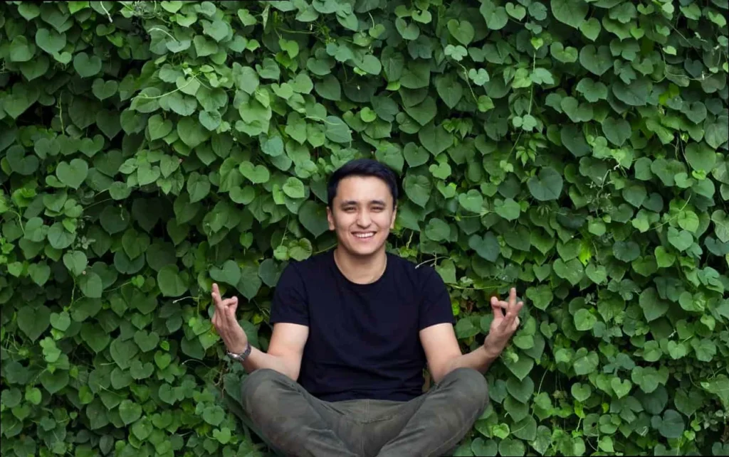 A man meditating peacefully in a lush green outdoor setting, embodying spiritual yoga and inner calm.