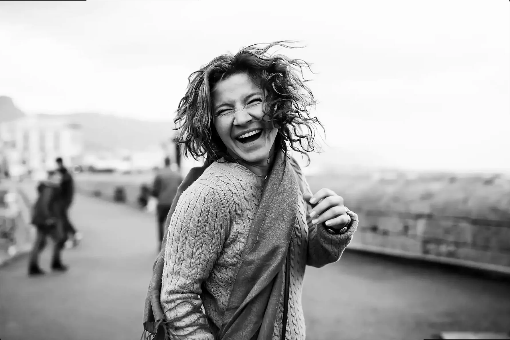 A black and white street photography shot of a person walking past a textured wall.