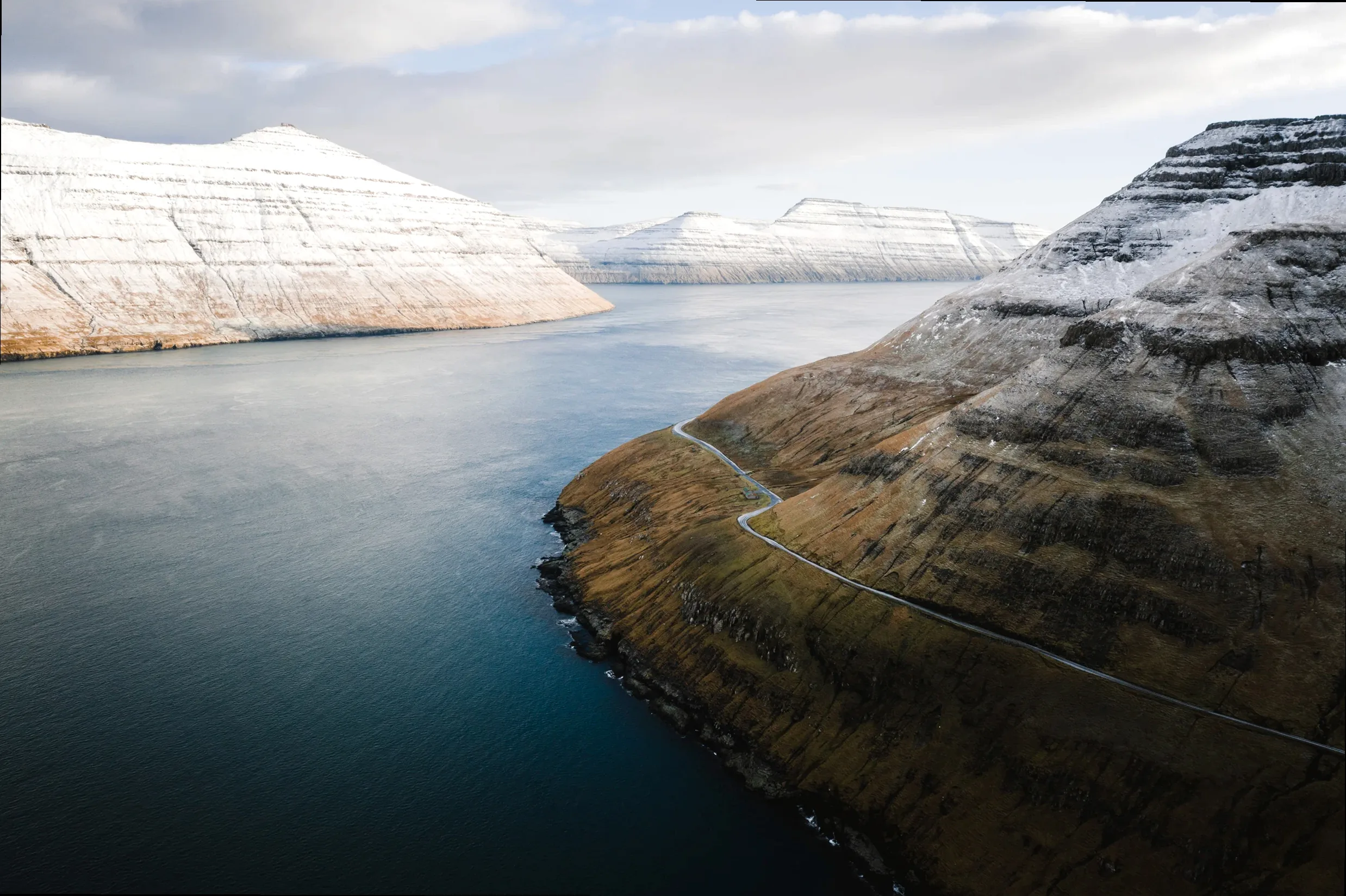 Dramatic landscape of the Faroe Islands with a small house, symbolizing discovery and the quiet stories held within remote travels.