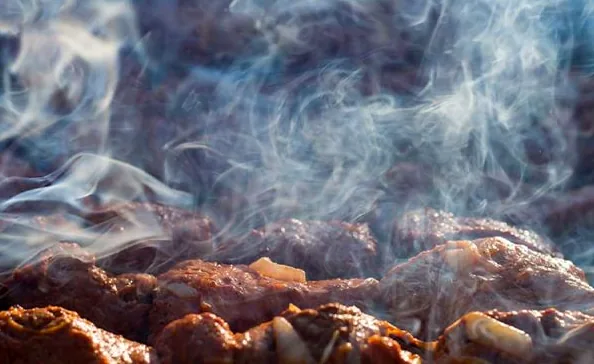 Close-up of a barbecue grill with smoke rising from perfectly cooked meat, evoking the classic aroma of a summer cookout.