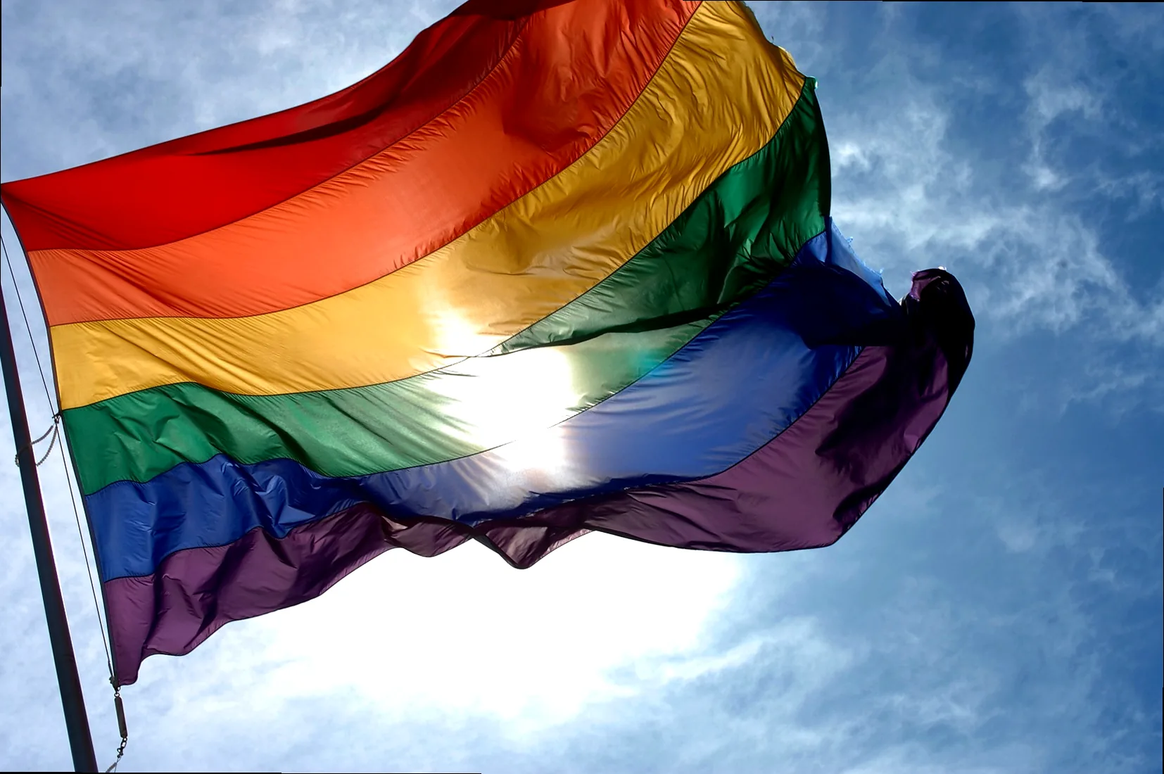 A vibrant rainbow flag against a clear blue sky, symbolizing hope and global LGBTQIA+ solidarity for IDAHOTB.