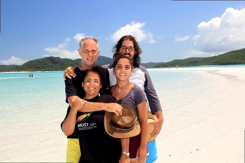 A happy family enjoying a serene moment together on a white sand beach, symbolizing togetherness and warmth.