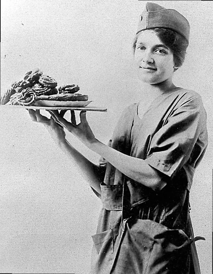 Cutting donut shapes from the rolled dough, a step that often involved makeshift tools during WWI.