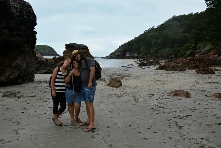 A mother and her children sharing a tender moment on a beach, embodying family love and warmth.