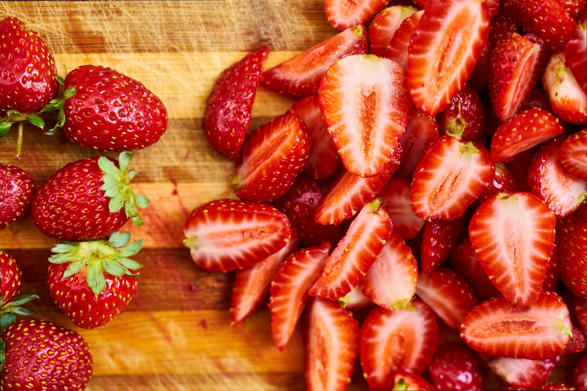 Hands gently picking ripe red strawberries from a lush green field, showing the joy of harvest.