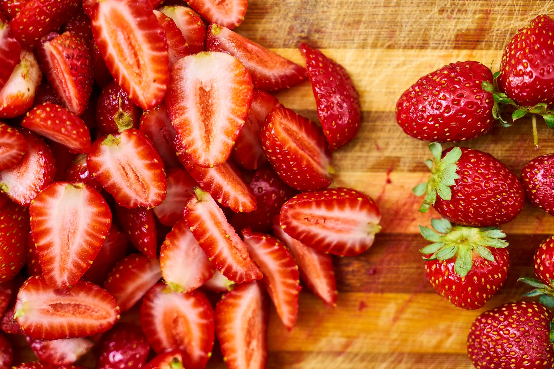 A hand holding a freshly picked, ripe strawberry in a field.